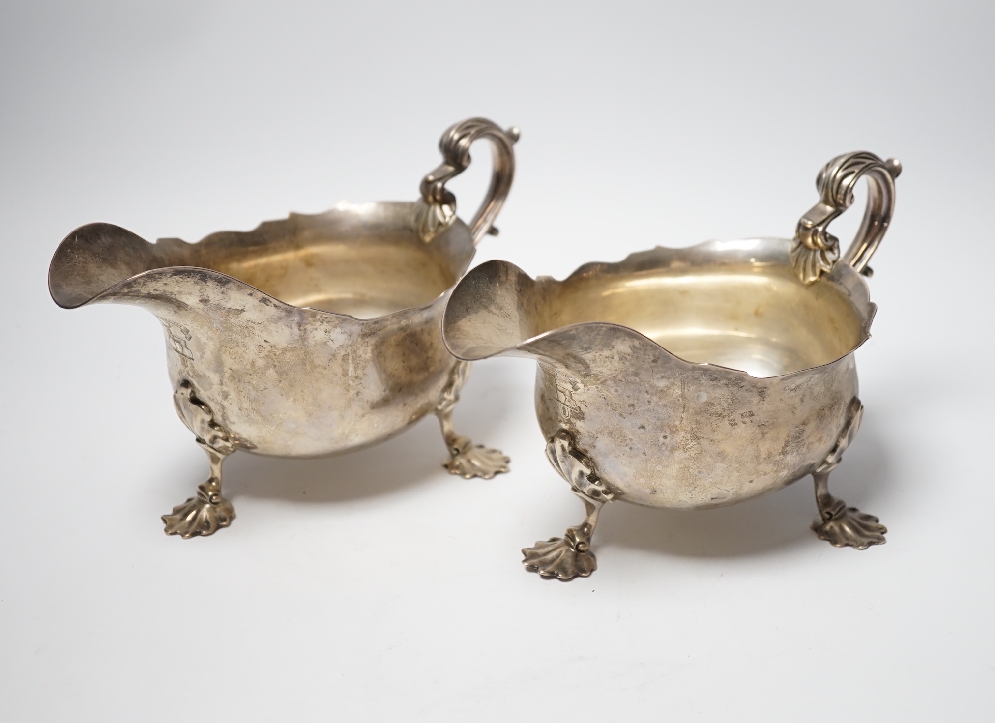 A pair of Edwardian silver sauce boats with shell knees, on three fluted feet, Carrington & Co, London, 1902, length 20.8cm, 33.9oz.
